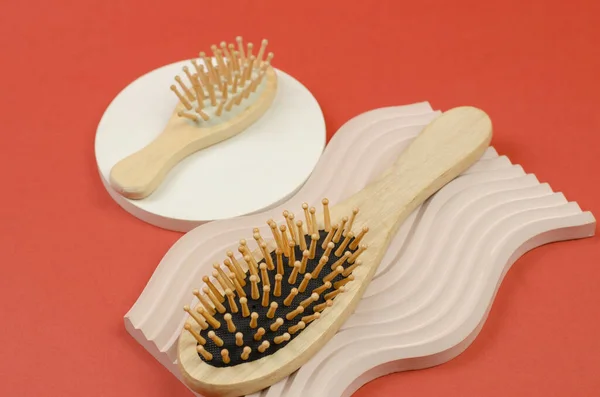 Hair brush made of natural material. Wooden hair combs on a beige plaster podium. Zero waste, no plastic