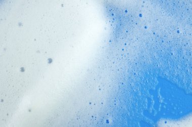 Mavi arka planda beyaz şampuan ya da deterjan köpüğünün makro fotoğrafı