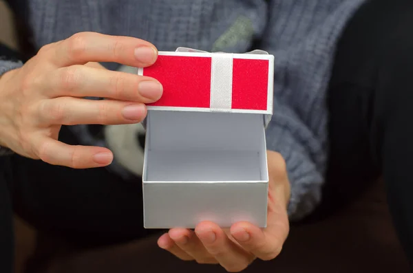 Open gift box in female hands, close-up. Woman opening a small gift box