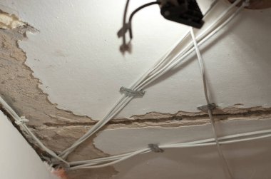 Tavana yeni kablolar döşeniyor. Elektrik kablolarının değiştirilmesi ve dağıtımı. Apartmanda tamirat var.