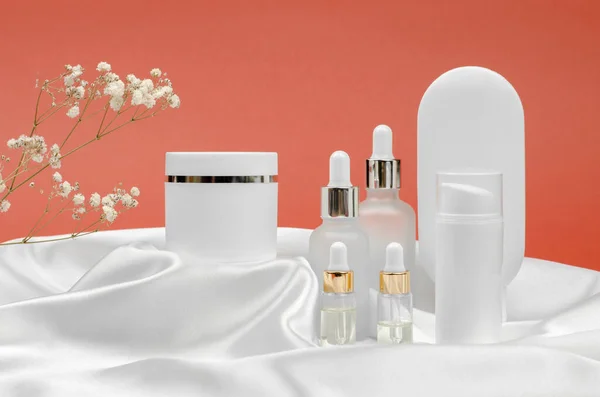 Cosmetic products on a podium made of silk fabric. Cream, mask, lotion and serum for face and body care.