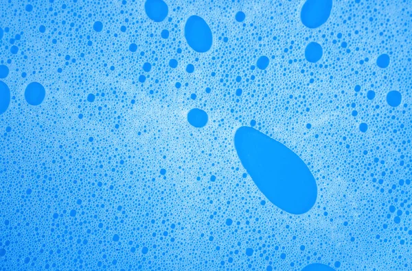 蓝色背景的白色洗发水或洗涤剂泡沫宏观照片 — 图库照片