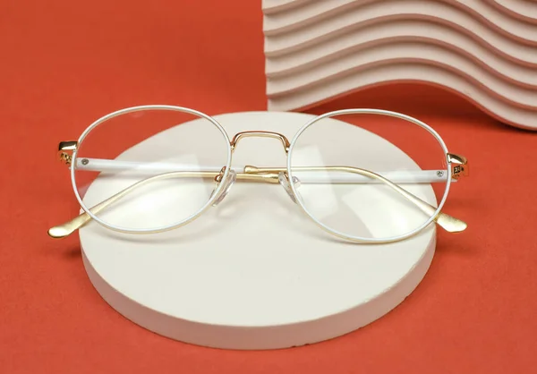 Stylish eyeglasses with a white frame on a round pedestal. Fashionable accessories.