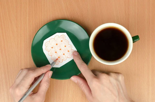 A cup of coffee on the table and a cookie drawn on a piece of paper on a saucer. Concept of economic crisis. Decrease in income. Lowering the standard of living.