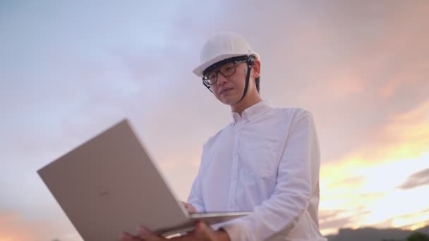 Asyalı Mühendis Boş Inşaat Sahasında Dizüstü Bilgisayarla Çalışırken Güvenlik Koruması — Stok video