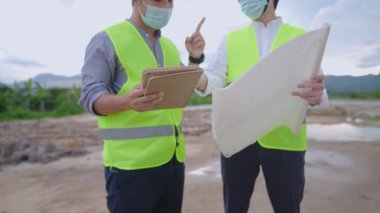 Erkek inşaat mühendislerini açık hava inşaat sahasında tartışmaya kapatın, dijital tabletle veri toplama, gayrimenkul fütürimenkul geliştirme ve planlama üzerine plan kullanarak mimar inşa edin.
