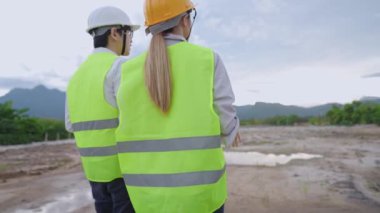 İki mutlu işçi kendilerini dışarıda çalışmaya, mühendislik sabah brifingine, düşük açılı çalışana doğal bir inşaat sahasında çalışmaya, iş pozisyonuna ve derecelendirme konseptine, arkadaşlığa ve takım çalışmasına hazırlıyorlar.