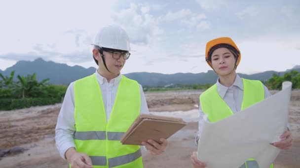 아시아의 엔지니어 건축은 현장에서 논의하는 장비를 착용하고 안전용 조끼와 헬멧을 — 비디오