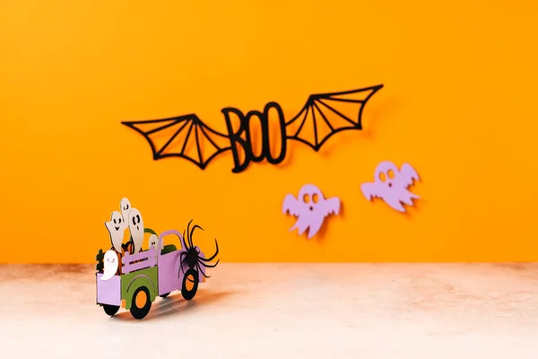 Happy halloween holiday concept. Halloween handmade paper decorations, spiders, ghosts in car, bats, boo text on orange background. Halloween festival party, greeting card mockup with copy space