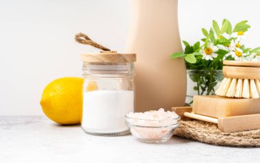 Çevre dostu doğal temizleyiciler, kabartma tozu dolu kavanoz, bulaşık fırçası, limon, çiçekler, beyaz arka planda sabun. Ev yapımı temizlik için organik malzemeler şişeyle temizleniyor. Sıfır atık kavramı, alanı kopyala