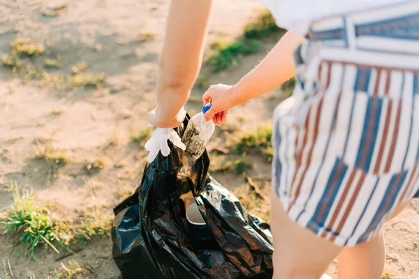 Jeune bénévole satisfaite de ramasser des ordures, des bouteilles en plastique et des tasses à café, nettoyer la plage avec une mer. Femme ramassant des ordures. Écologie environnementale concept de pollution. Jour de la Terre — Photo