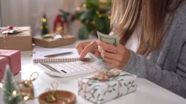 Kız Amerikan dolarlarını sayıyor, hesap makinesi kullanıyor ve masrafları yazıyor. Bütçeyle uğraşan bir kadın, alışveriş çılgınlığı için para dengesini hesaplıyor. Vergi ödeyen kadın muhasebeci. Kız Noel hediyelerini sayıyor