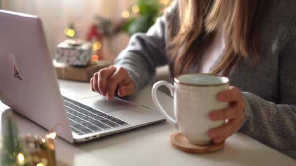 Detailní záběr ženských rukou, dárky, šálek kávy a notebook. Online nákupy o vánočních svátcích. Holka na volné noze se probouzí z kanceláře. Ženský píšou na notebooku. Vánoční chvíle — Stock video