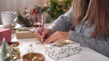 Noel hediyelerini paketleyen kadınların elleri, kapatın. Dekor elemanları ve ögeleri olan beyaz masada hazırlıksız hediyeler Noel veya Yeni Yıl Kutu Paketi