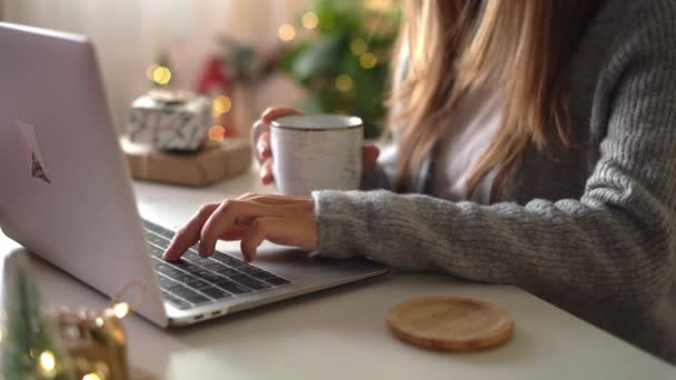 Detailní záběr ženských rukou, dárky, šálek kávy a notebook. Online nákupy o vánočních svátcích. Holka na volné noze se probouzí z kanceláře. Ženský píšou na notebooku. Vánoční chvíle — Stock video