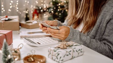 Kız Amerikan dolarlarını sayıyor, hesap makinesi kullanıyor ve masrafları yazıyor. Bütçeyle uğraşan bir kadın, alışveriş çılgınlığı için para dengesini hesaplıyor. Vergi ödeyen kadın muhasebeci. Kız Noel hediyelerini sayıyor