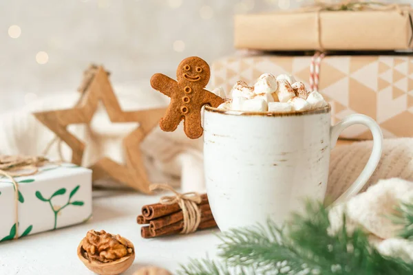 Gingerbread man cookie in cup of hot cocoa or coffee with marshmallow, fir tree, gifts and warm cozy sweater. Christmas greeting card, lights background. Xmas holiday eco natural decorations — Stock Photo, Image