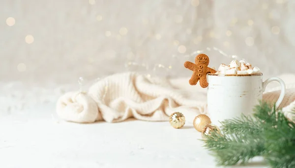 Gingerbread man cookie in cup of hot cocoa or coffee with marshmallow, fir tree, cinnamon and warm cozy sweater. Christmas banner, lights background. Xmas holiday decorations with copy space — Stock Photo, Image