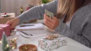 Kız Amerikan dolarlarını sayıyor, hesap makinesi kullanıyor ve masrafları yazıyor. Bütçeyle uğraşan bir kadın, alışveriş çılgınlığı için para dengesini hesaplıyor. Vergi ödeyen kadın muhasebeci. Kız Noel hediyelerini sayıyor