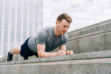 Genç adamın fitness antrenmanı var. Erkek sporcu karın kası egzersizi, spor ve antrenman yapar ve tahta üzerinde durur. İnsanlar spor ve sağlıklı yaşam tarzı konsepti