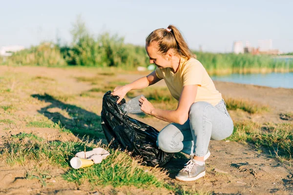 Junge Ehrenamtliche sammeln Müll, Plastikflaschen und Kaffeetassen, säubern Strand und Meer. Frau beim Müllsammeln. Umweltökologisches Verschmutzungskonzept. Tag der Erde — Stockfoto