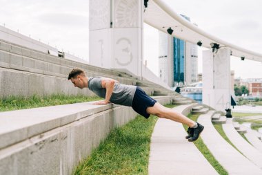 Genç adamın fitness antrenmanı var. Erkek sporcu karın kası egzersizi, spor ve antrenman yapar ve tahta üzerinde durur. İnsanlar spor ve sağlıklı yaşam tarzı konsepti