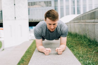 Genç adamın fitness antrenmanı var. Erkek sporcu karın kası egzersizi, spor ve antrenman yapar ve tahta üzerinde durur. İnsanlar spor ve sağlıklı yaşam tarzı konsepti