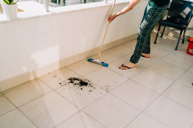 Man wiping floor with the mop. Janitor washing the dirty floors. Guy mopping the balcony on a sunny day. Person doing home chores. Young fellow using cleaning equipment to dust the surface