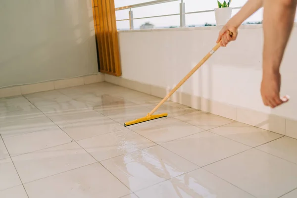Man wiping floor with the mop. Janitor washing the dirty floors. Guy mopping the balcony on a sunny day. Person doing home chores. Young fellow using cleaning equipment to dust the surface — Foto de Stock