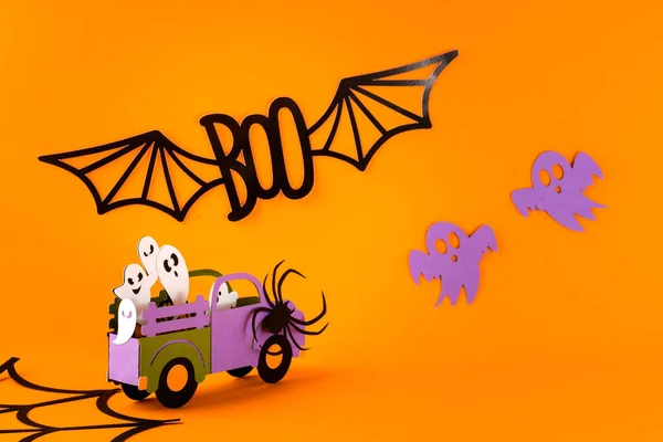 Happy halloween holiday concept. Halloween handmade paper decorations, spiders, ghosts in car, bats, boo text on orange background. Halloween festival party, greeting card mockup with copy space.