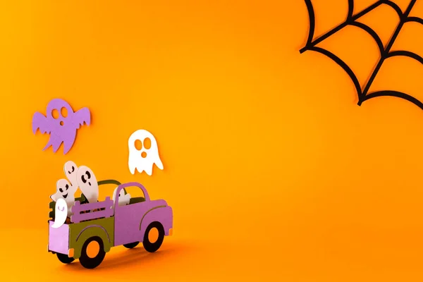 Happy halloween holiday concept. Halloween handmade paper decorations, spiders, spider web, ghosts in car on orange background. Halloween festival party, greeting card mockup with copy space.