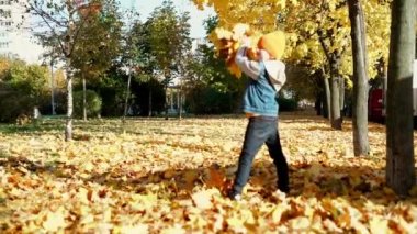 Father and son having fun in autumn park with fallen leaves, throwing up leaf. Child kid boy and his dad outdoors playing with maple leaves