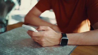 Bir sokak kafeteryasındaki kahve dükkanında erkek eli cep telefonu cihazını tutuyor. Merhaba yaz tatili.