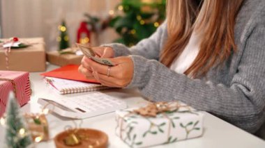 Kız Amerikan dolarlarını sayıyor, kırmızı zarflara sarılıyor. Bütçeyle uğraşan bir kadın, alışveriş çılgınlığı için para dengesini hesaplıyor. Vergi ödeyen kadın muhasebeci. Kız Noel hediyelerini sayıyor.