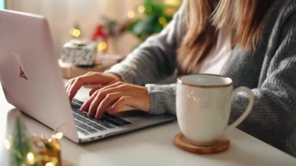 女性の手を閉じます 贈り物 コーヒーカップとラップトップ クリスマス休暇でオンラインショッピング フリーランスの女の子は 自宅のオフィスから歩く ノートパソコンで入力する女性 クリスマスの瞬間 — ストック動画