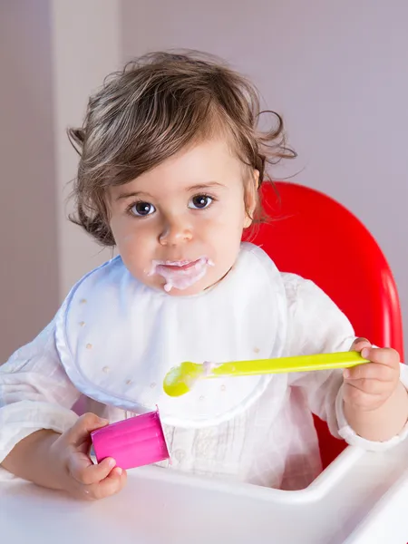Bebé comiendo yogur con la cara desordenada —  Fotos de Stock
