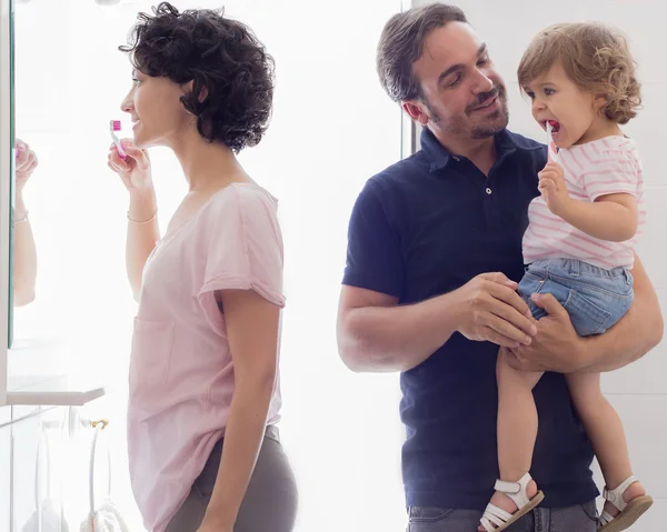 Familia cepillando dientes en espejo de baño — Foto de Stock