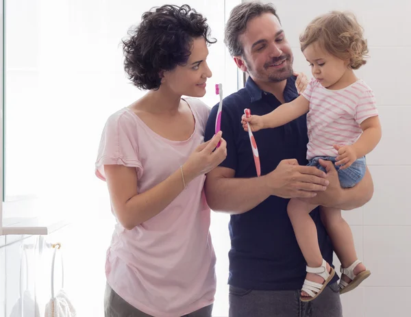 Moeder en vader onderwijzen hun dochter haar tanden te poetsen — Stockfoto