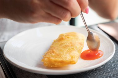 Geleneksel baharatlı börekler ve restoranda beyaz tabakta tatlı biber sosu..