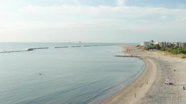 Şemsiyeli, çarşaflı ve kasabalı kumlu sahil manzarası. Lido Adriano kasabası, Adriyatik kıyısı, Emilia Romagna, İtalya.