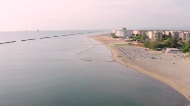 Şemsiyeli ve gazeli kumlu sahil manzarası. Lido Adriano kasabası, Adriyatik kıyısı, Emilia Romagna, İtalya..