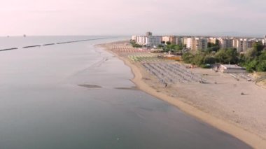 Şemsiyeli ve gazeli kumlu sahil manzarası. Lido Adriano kasabası, Adriyatik kıyısı, Emilia Romagna, İtalya..