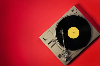 Kırmızı masadaki vinil plaklı gramofon, üst görünüm ve kopyalama alanı, eski tarz için bölünmüş ton.