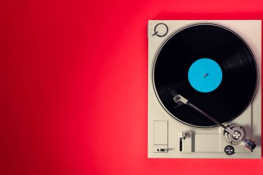 Kırmızı masadaki vinil plaklı gramofon, üst görünüm ve kopyalama alanı, eski tarz için bölünmüş ton.