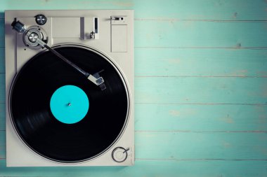 Gramophone with a vinyl record on wooden table, top view and copy space,split toning effect for old style.