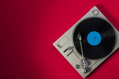 Kırmızı arkaplan, üst görünüm ve boşluk kopyalama üzerine vinil plaklı gramofon.