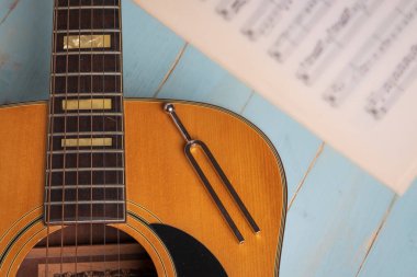 Gitar, müzik kağıtları ve ahşap masadaki çatalla müzik kaydı sahnesi, yakın plan.