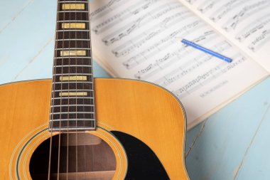 Gitar, nota kağıdı ve kalemle ahşap masada müzik kaydı sahnesi, yakın plan.
