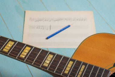 Gitar, nota kağıdı ve kalemle ahşap masada müzik kaydı sahnesi