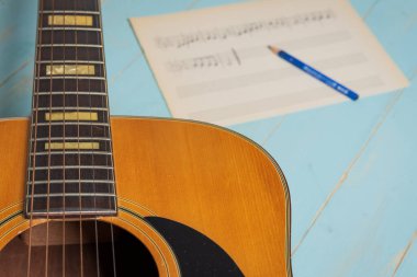 Gitar, nota kağıdı ve kalemle ahşap masada müzik kaydı sahnesi
